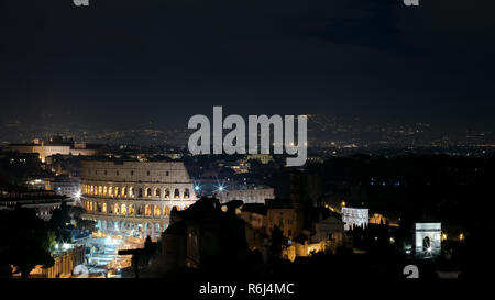 Panoramica vista notturna di Roma. In primo piano il Colosseo illuminato, sulla destra dell'Arco di Costantino e la zona dei Fori Imperiali wi Foto Stock