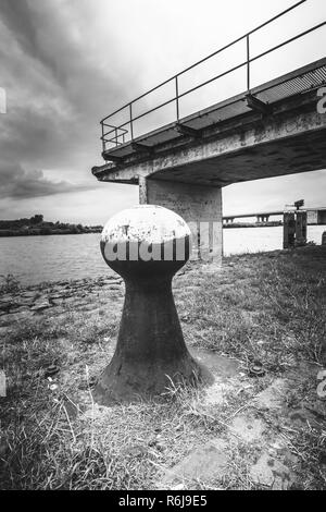Vecchio e decrepito bastione vintage lungo il lungomare in un fiume landaschap dei Paesi Bassi. Calcestruzzo a getto di ormeggio in stato di abbandono. Foto Stock