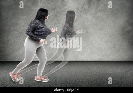 Plus-dimensionato donna corre per la sua sottile ombra sul muro, il concetto di perdita di peso Foto Stock