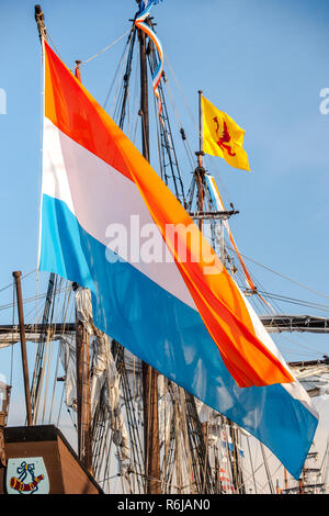 Colorata bandiera olandese svolazzanti sul giorno nuvoloso sul ponte di poppa di un di legno storico olandese in barca a vela Foto Stock