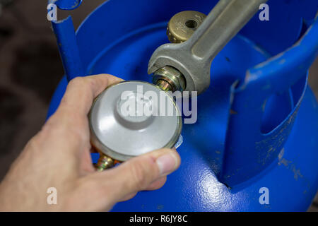 Regolatore per propan-butano bombola del gas e accessori su un workshop in legno tavolo. Accessori per gas in officina. Sfondo scuro. Foto Stock