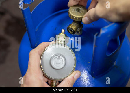Regolatore per propan-butano bombola del gas e accessori su un workshop in legno tavolo. Accessori per gas in officina. Sfondo scuro. Foto Stock