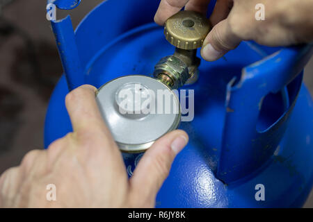 Regolatore per propan-butano bombola del gas e accessori su un workshop in legno tavolo. Accessori per gas in officina. Sfondo scuro. Foto Stock