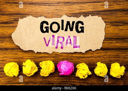 Testo della scrittura andando virale. Concetto di social business virale scritto su una nota adesiva carta promemoria, sullo sfondo di legno con appiccicoso, una carta piegata da soli per differenza o collaborazione Foto Stock