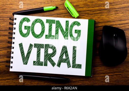 Annuncio della scrittura testo che mostra andando virale. Il concetto di business per il Social Business virale scritto sul libro dei notebook nota la carta sullo sfondo di legno. Parola verde lettere. Accanto al mouse. Foto Stock