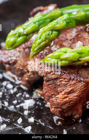 Bistecca di manzo e asparagi verdi in una padella Foto Stock