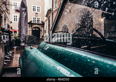 Lato di auto d'epoca in gocce di pioggia parcheggiata su una stretta strada di città; Abstract sfondo vintage Foto Stock