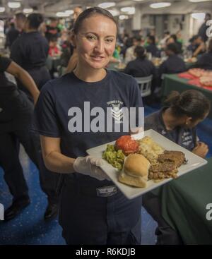 Golfo Arabico (20 maggio 2017) Electronics Tecnico 1a classe Joanna Waugh serve una piastra per la Festa della Mamma la cena a bordo della portaerei USS George H.W. Bussola (CVN 77) (GHWB). GHWB è distribuito negli Stati Uniti Quinta Flotta area di operazioni a sostegno della sicurezza marittima operazioni destinate a rassicurare gli alleati e partner e preservare la libertà di navigazione e il libero flusso di commercio nella regione. Foto Stock