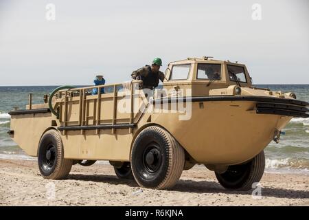 VENTSPILS, Lettonia- marinai con unità Beachmaster due, Navale Beach gruppo due, Expeditionary Strike gruppo due, operare un accendino di rialimentazione anfibio Cargo 5 ton in preparazione per esercitare Saber Strike 17 in Ventspils, Lettonia, 22 maggio 2017. Esercizio Saber Strike 17 è un annuale combinati-esercizio congiunto condotti presso varie sedi in tutta la regione del Mar Baltico e della Polonia. La combinazione di corso di formazione prepara gli alleati e partner per rispondere più alle crisi regionali e di soddisfare le loro esigenze di sicurezza mediante il miglioramento della sicurezza delle frontiere e la lotta contro le minacce. Foto Stock