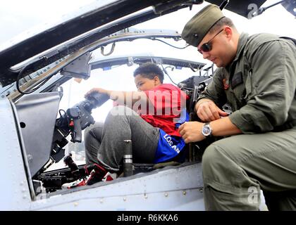 Un bambino si trova all'interno della cabina di pilotaggio di un AH-1W Super elicottero Cobra durante un tour a bordo della USS Kearsarge (LHD 3) come parte della flotta settimana New York 2017, 27 maggio 2017. Marines, marinai e la costa guardie chaperoned 20 bambini partecipanti alla undicesima edizione del Progetto Speranza. Foto Stock