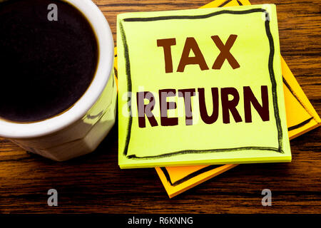 Il testo scritto a mano che mostra il ritorno fiscale. Il concetto di business per la Fiscalità rimborso scritto su una nota adesiva sulla carta il legno in legno sfondo con tazza di caffè Foto Stock