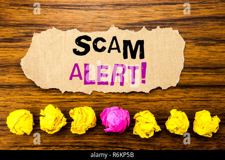 Testo della scrittura Scam Alert. Concetto per Avviso di frode scritto su una nota adesiva carta promemoria, sullo sfondo di legno con appiccicoso, una carta piegata da soli per differenza o collaborazione Foto Stock