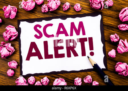 La scrittura a mano didascalia di testo ispirazione mostra Scam Alert. Il concetto di business per Avviso di frode scritto su una nota adesiva carta, sullo sfondo di legno con piegata carta rosa significato pensare Foto Stock