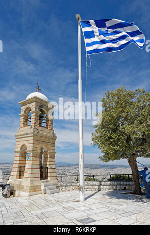 ATHENS, Grecia - 02 Maggio: Simboli greci a Monte Lycabettus ad Atene il 02 maggio, 2015. Bandiera Greca torre campanaria e l albero di olivo nella sommità del monte Lycabettos Foto Stock