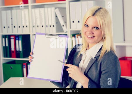 Young business woman in office puntando al clipboard Foto Stock