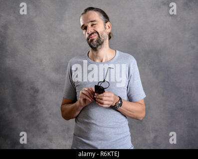 Giovane uomo barbuto ceaning i suoi occhiali Foto Stock