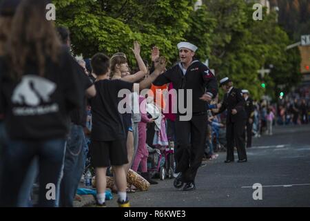 SPOKANE, Washington. (20 maggio 2017) marinai da Naval Operations Support Center (NOSC) Spokane alta cinque membri della folla durante lo Spokane Lilla del Festival 2017 Forze Armate Torchlight Parade. Dal 2005, la Marina programma settimana ha servito come la Marina Il principale sforzo di divulgazione in aree del paese senza una significativa presenza della Marina, con 195 Navy settimane svoltasi in 71 diverse città degli Stati Uniti. Il programma è stato progettato per aiutare gli americani a capire che il loro Marina è distribuito in tutto il mondo, circa l'orologio, pronto a difendere l'America in tutti i tempi. Foto Stock