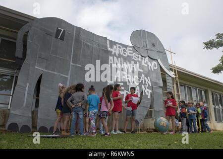 Bambini da Kadena Scuola Elementare si raccolgono intorno ad un ritaglio di cartone del mondo la più grande terra-walking animale, un elefante africano, 22 maggio 2017, a Kadena Air Base, Giappone. L'evento prodotte dai membri della scuola di Inglese come seconda lingua e il team si è tenuto a insegnare interdisciplinare temi come la scienza, la salute, la storia e la geografia. Foto Stock