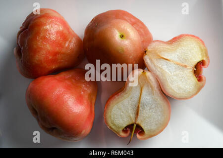 Le mele di cera (aka Rose mele - Syzygium samarangense) su una piastra bianca, compresa una mostra in sezione trasversale. Foto Stock