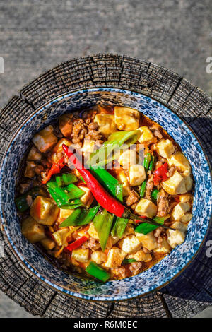 Mapo Tofu - tofu, carne di maiale e le verdure in una piccante salsa cinese, overhead mostrata in una ciotola su una superficie in legno Foto Stock