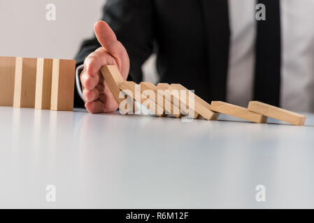 Crisi aziendale concetto di soluzione con il business manager di intervenire per fermare il collasso dei Dominos. Foto Stock