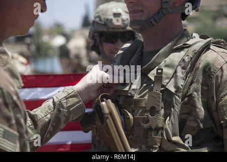 Stati Uniti Esercito il Mag. Gen. Giuseppe Martin, il comandante generale combinata di forze congiunte terra comando di componente e 1a divisione di fanteria, promuove il Mag. Timothy Batig, assegnati al 2° Battaglione, 2° Brigata Team di combattimento, ottantaduesima Airborne Division, per il grado di tenente colonnello al fianco di iracheni e i partner della coalizione a Mosul, Iraq, 25 maggio 2017. La seconda BCT, ottantaduesima Abn. Div., consente loro ISF partner attraverso il consigliare e assistere la missione, contribuendo pianificazione, raccolta di intelligence e di analisi, forza di protezione, e gli incendi di precisione per ottenere la sconfitta militare di Iside. CJTF-funzione OIR è il global Co Foto Stock