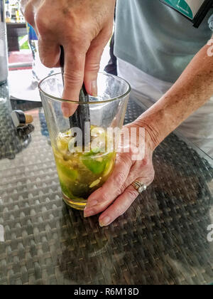 Creare un cocktail di concorrenza a Mount Gay distillery a Bridgetown, Barbados. Questo ragazzo sa di cosa sta facendo come egli muddles lime e lo zenzero Foto Stock