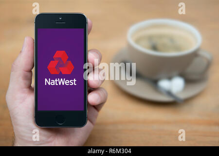 Un uomo guarda al suo iPhone che visualizza la Natwest logo (solo uso editoriale). Foto Stock