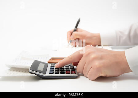 Le mani di imprenditore iscritto una ricevuta su un notebook, close-up. Foto Stock