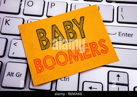 Mano concettuale di scrittura di testo Didascalia ispirazione che mostra i baby boomer. Il concetto di business per la generazione di dati demografici scritto su una nota adesiva sulla carta il bianco sullo sfondo della tastiera. Foto Stock