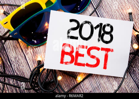 La scrittura di un testo che mostra 2018 Migliore. Il concetto di business per scelta recensione scritta su una nota adesiva con copia spazio su legno vecchio sfondo di legno con occhiali da sole Foto Stock