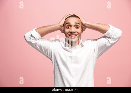 Il giovane uomo attraente cercando sorpresi isolati su rosa Foto Stock