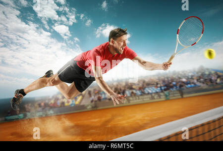 Un lettore di salto, caucasiche montare l'uomo, giocando a tennis sulla corte di terracotta con gli spettatori Foto Stock