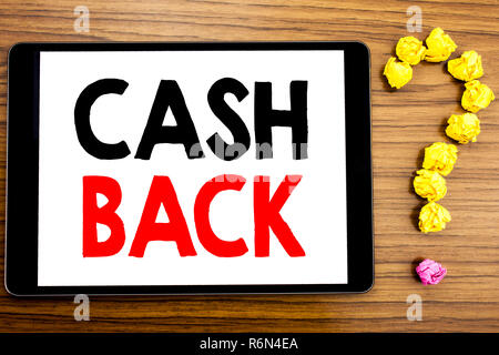 La scrittura di un testo che mostra il Cash Back Cashback. Il concetto di business per denaro garanzia scritta su tablet PC sullo sfondo di legno con un punto interrogativo in carta ripiegata. Foto Stock