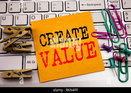La scrittura di un testo che mostra la creazione di valore. Il concetto di business per creare motivazione scritta su una nota adesiva sulla carta il bianco sullo sfondo della tastiera. Foto Stock