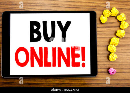La scrittura di un testo che mostra acquista online. Il concetto di business per l'E-commerce acquisto vendita scritto su tablet PC sullo sfondo di legno con un punto interrogativo in carta ripiegata. Foto Stock