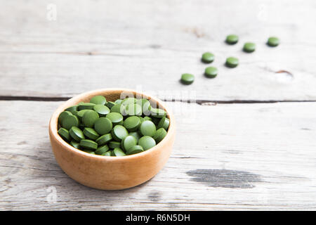 Pillole di verde spirulina o clorella alga nella ciotola di legno verde orzo chlorella Foto Stock