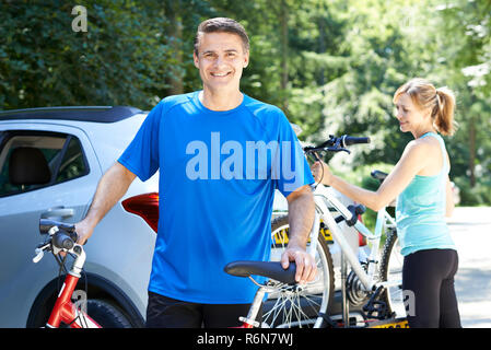 Coppia Matura prendendo le mountain bike da cremagliera sulla macchina Foto Stock