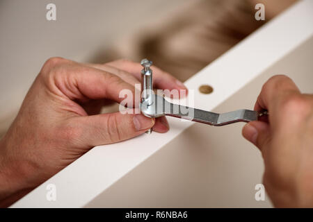 Close up sulle mani con una chiave assemblaggio di mobili. Foto Stock