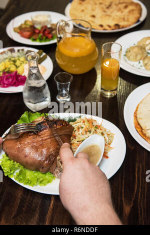 L'uomo mangia gustoso piatto di stinco di maiale Foto Stock