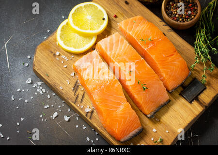 Pesce fresco. Materie Filetto di salmone, limone e spezie su un rustico di legno su un tavolo di pietra. Copia dello spazio. Foto Stock