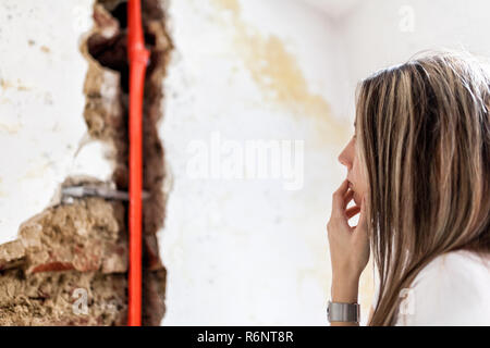Donna che guarda la danno dopo un tubo di acqua di perdita Foto Stock