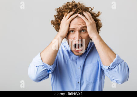 Ritratto di un giovane sconvolto l uomo indossa shirt standing isolate su uno sfondo grigio, urlando Foto Stock