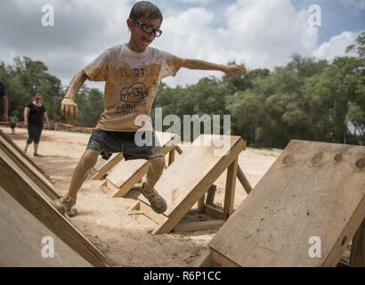 Aidan Flippo, pilota per un giorno candidato, completa un ostacolo durante una carità fango-run 20 maggio 2017, a Niceville, Florida. Flippo è stata selezionata per essere la trentatreesima Fighter Wing il pilota per un giorno. Aidan è nato con ottica Septo displasia effetti che i suoi occhi e reni. Durante la sua giornata ha incontrato F-35 piloti, ha girato un aeromobile, ha lavorato con un aeromobile con i manutentori e molto di più. Foto Stock