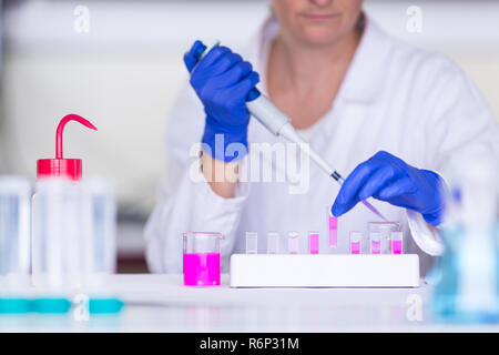 Le mani di un ricercatore femmina svolgendo attività di ricerca in un laboratorio di chimica (colore immagine dai toni shallow DOF) Foto Stock