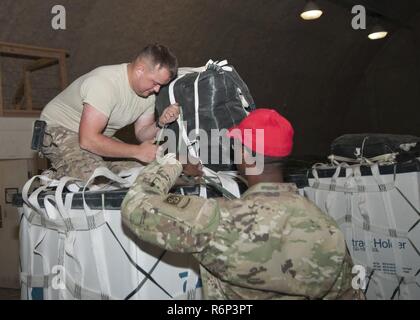 Spc. Alexander Triska e SPC. Keith effettivi della 824th Quartermaster Company, fissare un paracadute per un contenitore per la consegna dell'antenna Al Udeid Air Base, Qatar il 25 aprile 2017. Antenna le operazioni di consegna sono essenziali per ottenere le forniture alle truppe in Medio Oriente quando i normali mezzi di trasporto non sono fattibili. Foto Stock