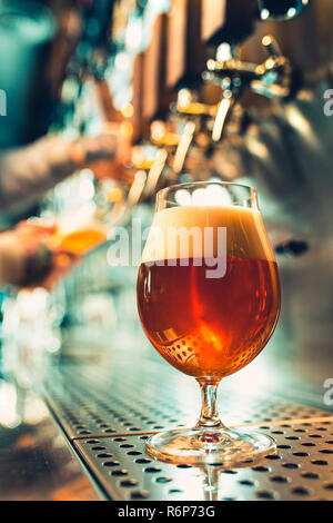 Mano del barista versando una grande birra lager in tap. Foto Stock