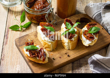 Antipasti italiani snack per il vino. Spaghetti con formaggio morbido e pomodori secchi su di un tavolo di legno. Foto Stock