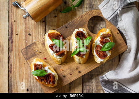 Antipasti italiani snack per il vino. Spaghetti con formaggio morbido e pomodori secchi su di un tavolo di legno. Foto Stock