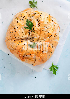 Torta greca spanakopita su sfondo blu. Vegetariano o Vegano Spanakopita Spinaci torta di pasta fillo. Copia dello spazio. Idee e ricette per una sana pausa pranzo. Vista superiore piatta o laici. Verticale. Foto Stock